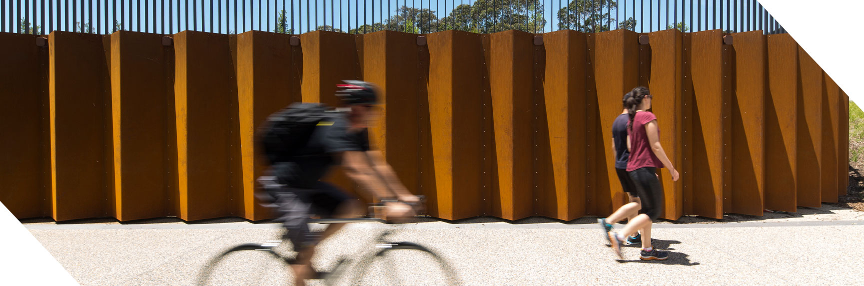 action shot of man cycling in front of sculpture