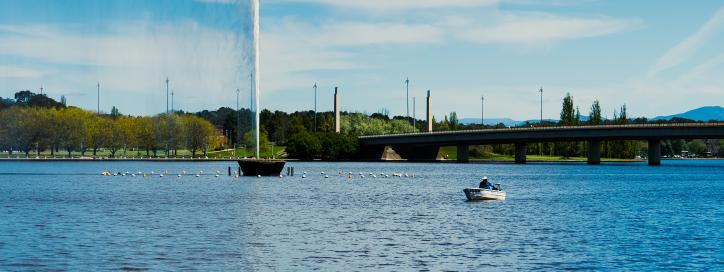 Lake Burley Griffin with Captain Cook Memorial Jet in Operation as Boat User drives by.