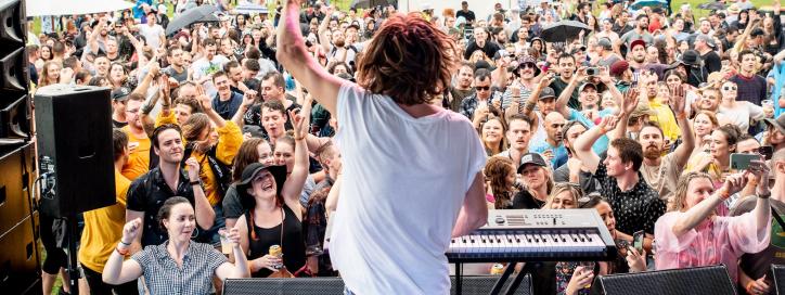 View from main stage featuring back of performer and view of festival crowd before him.