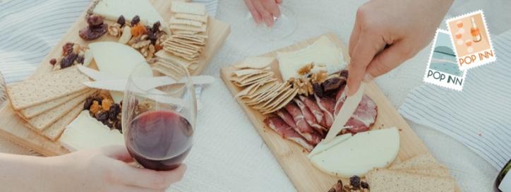 Image of hands holding red wine and cutting cheese