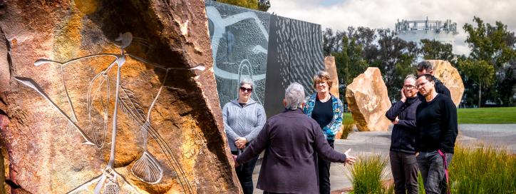 Tour Guide, arms spread out wide, discusses Artworks at Reconciliation Place