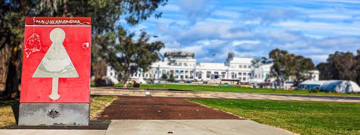 Photo of old, red, barely legible sign with Old Parliament House in the background