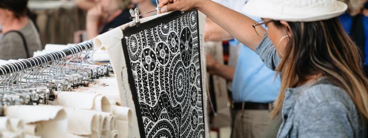 A woman examines a black and white painting at the AIATSIS indigenous art market.