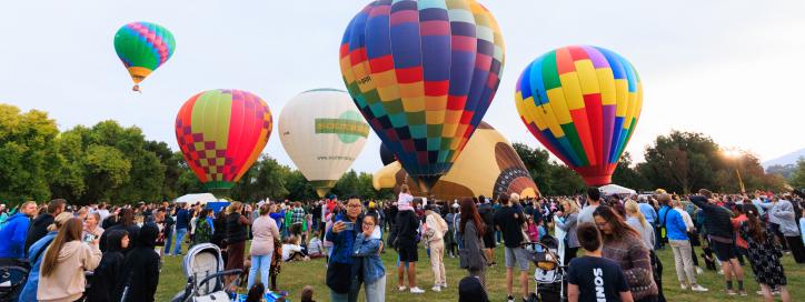 People loving life and balloons in front of an early morning sky