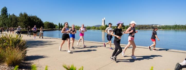Several people running along the lake