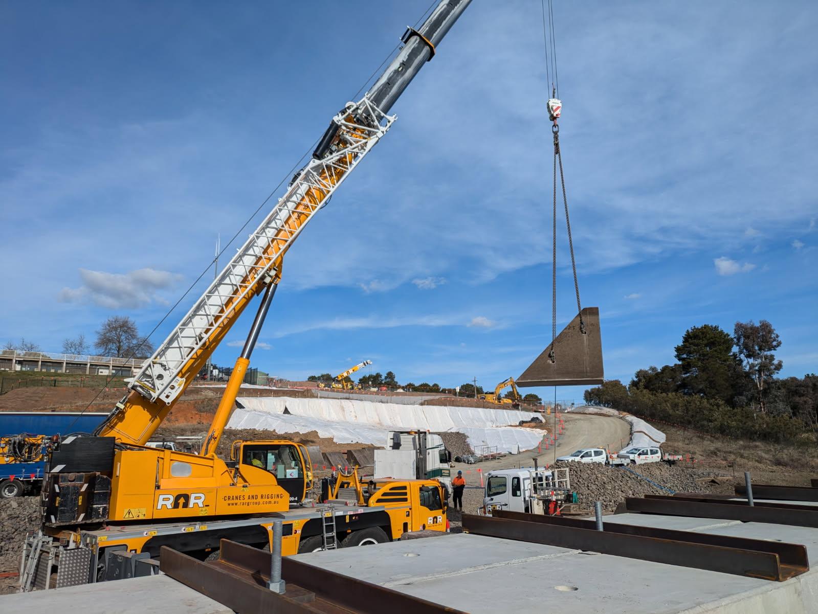 This image shows a crane onsite lifting a baffle block.