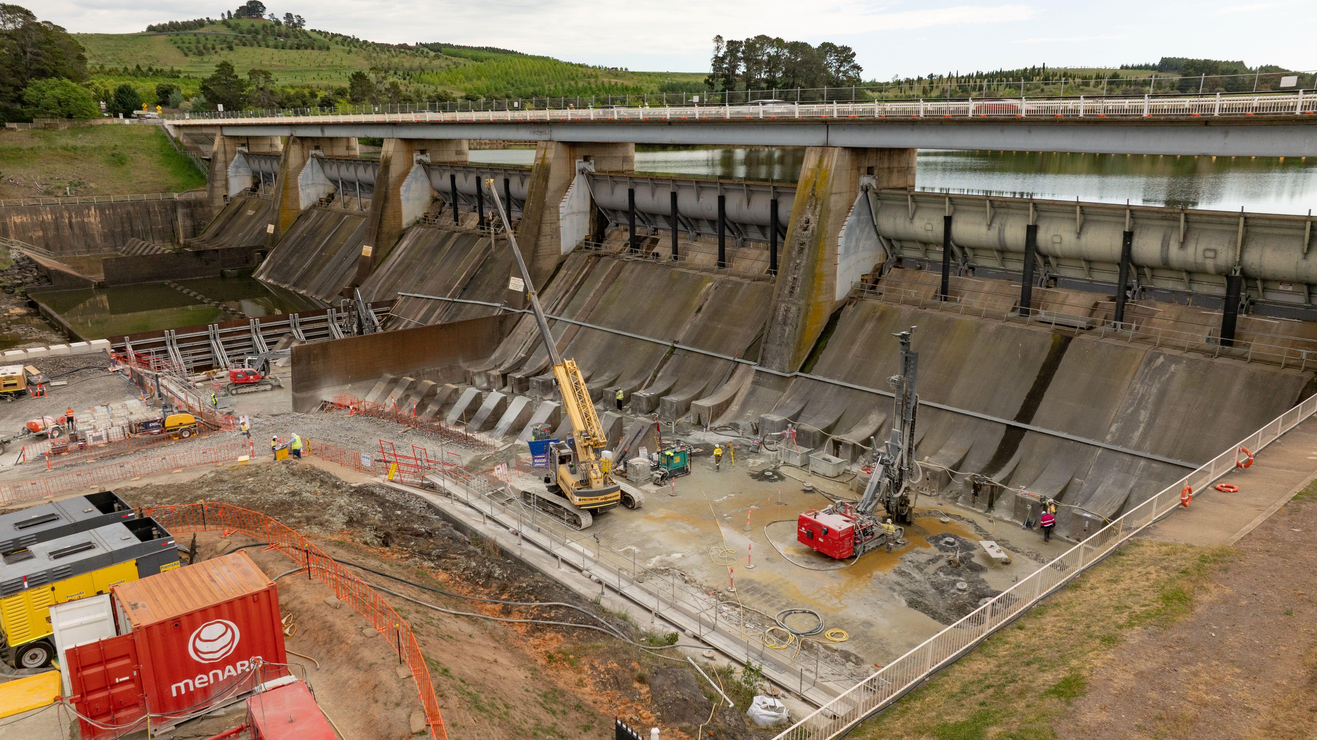 Wide lens shot of construction underway at Scrivener Dam including drilling and crane movements