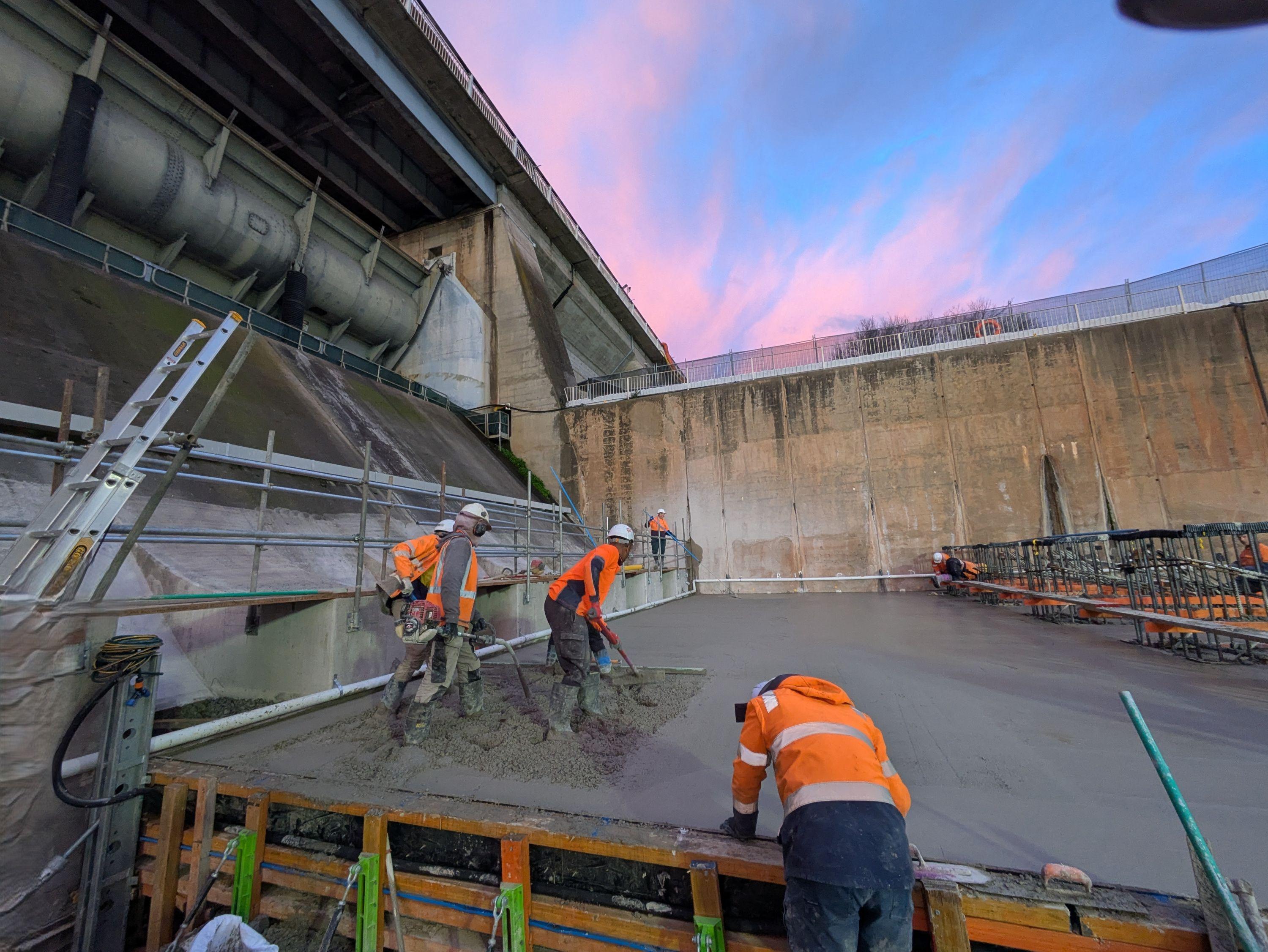 This image is a close up of three workers laying the concrete within the slab.