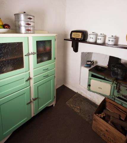 An old aga stove and green cupboard,with tins on the mantle 