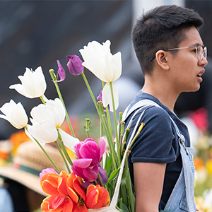 A person in glasses carrying beautiful flowers in a backpack