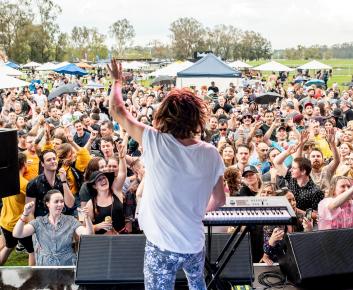 View from main stage featuring back of performer and view of festival crowd before him.