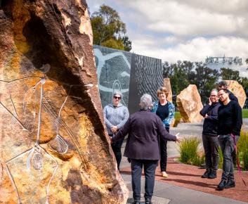Tour Guide, arms spread out wide, discusses Artworks at Reconciliation Place