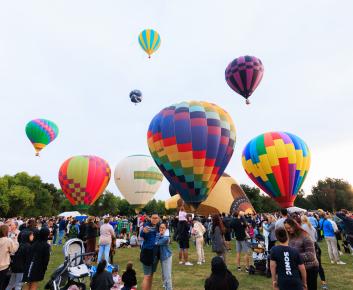 People loving life and balloons in front of an early morning sky