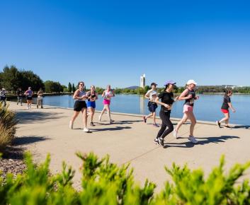 Several people running along the lake
